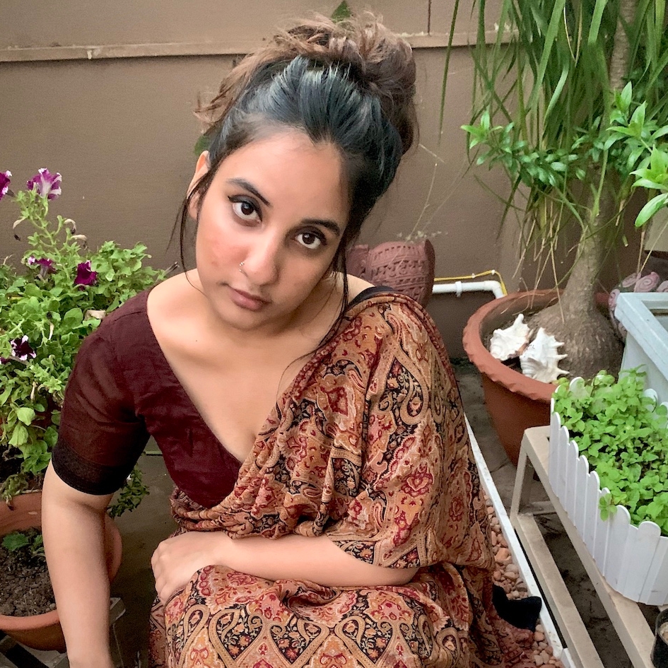Bidisha wears saree and looks up to the camera surrounded by plants